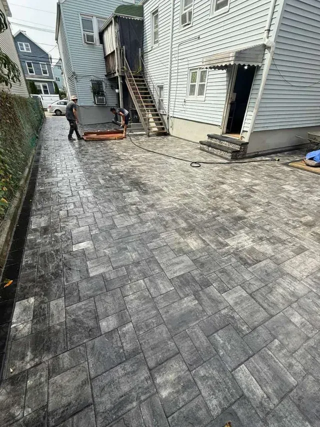 Newly paved alley with workers; buildings in background. Gray paving stones.
