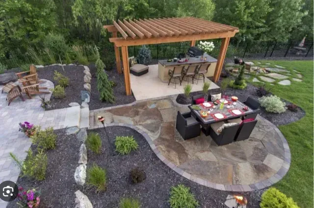 Overhead view of a backyard patio with a pergola-covered bar, dining table, and landscaped garden.