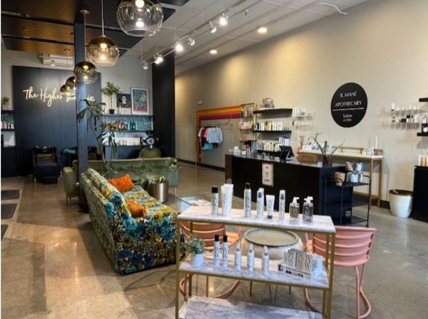 Modern cafe interior with display shelves, seating, and a pastry counter in soft pastel colors