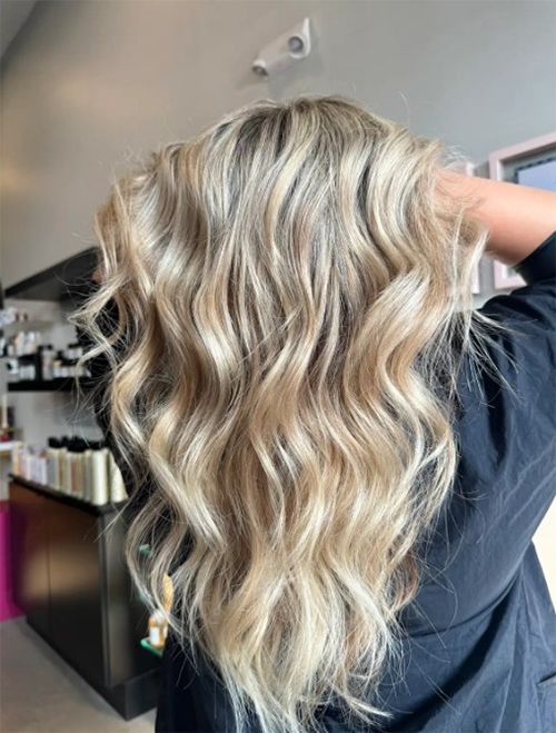 Back view of wavy, multi-tonal blonde hair with lighter highlights in a salon setting.