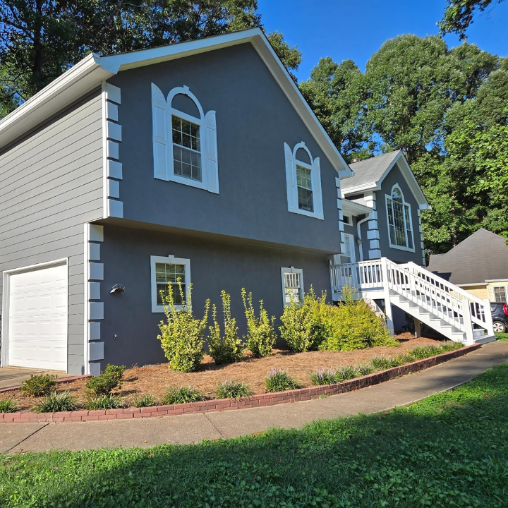 A gray house with white trim and arched windows