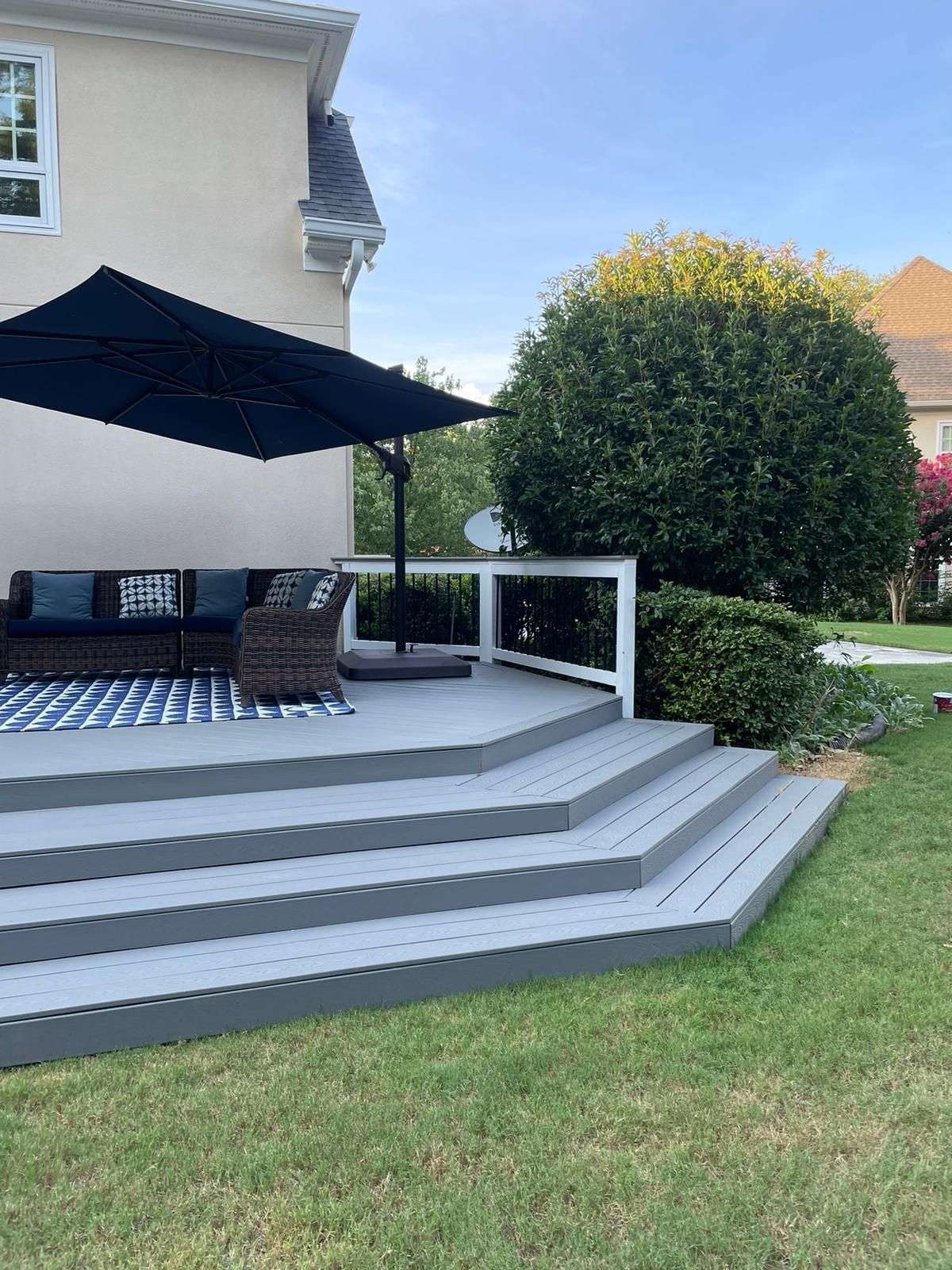 A large deck with stairs and umbrellas in front of a house.