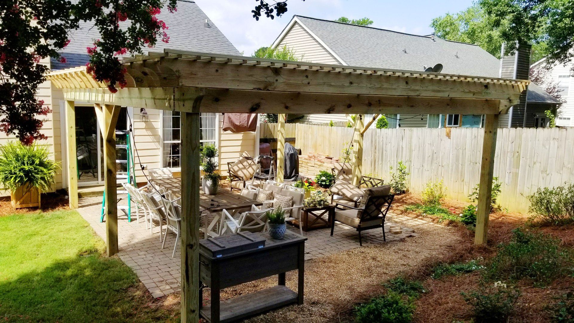 A wooden pergola is sitting in the backyard of a house.