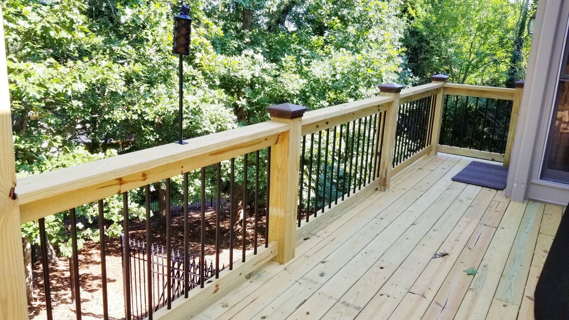A wooden deck with a metal railing and trees in the background.