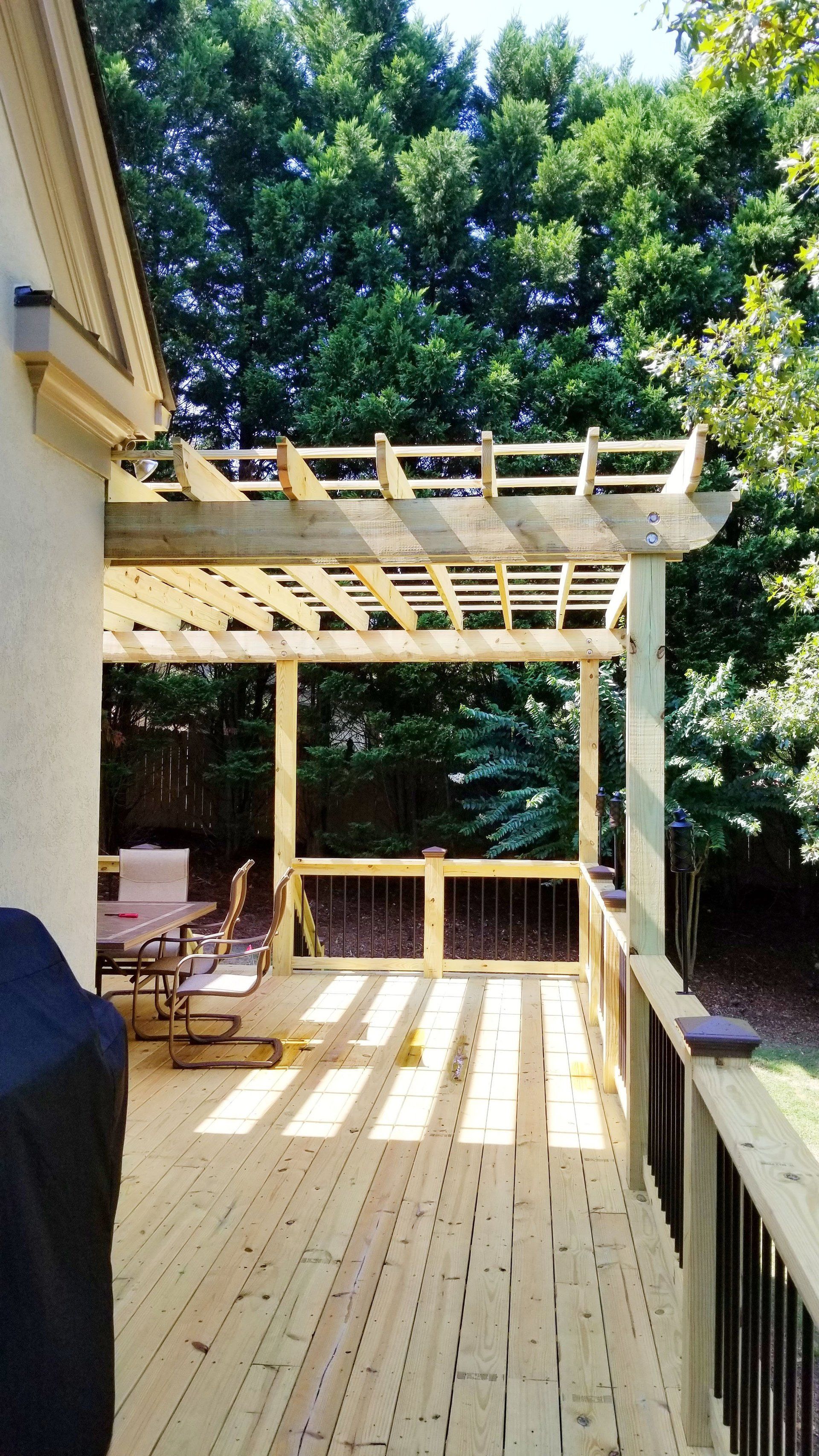 A good-looking wooden deck with a pergola on top of it.