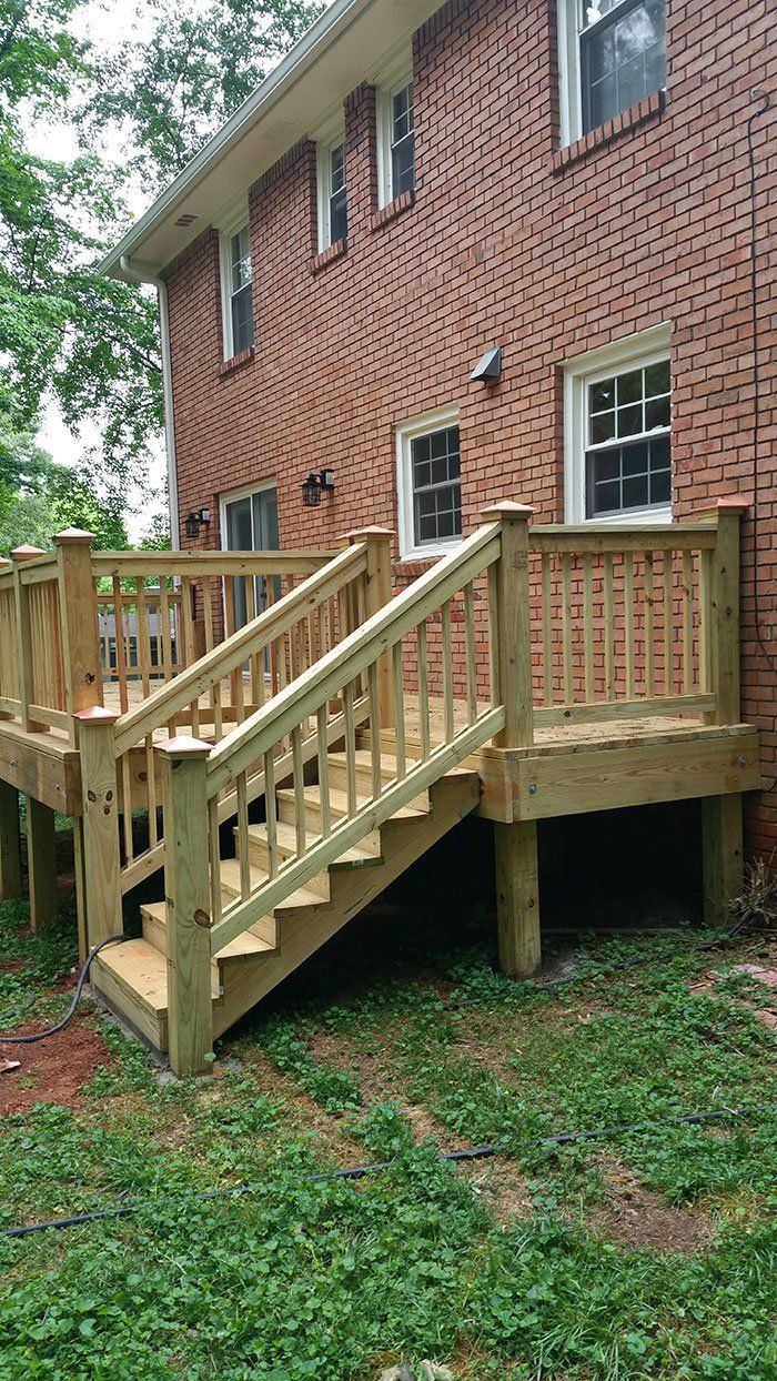 A wooden deck with stairs leading up to a brick house.