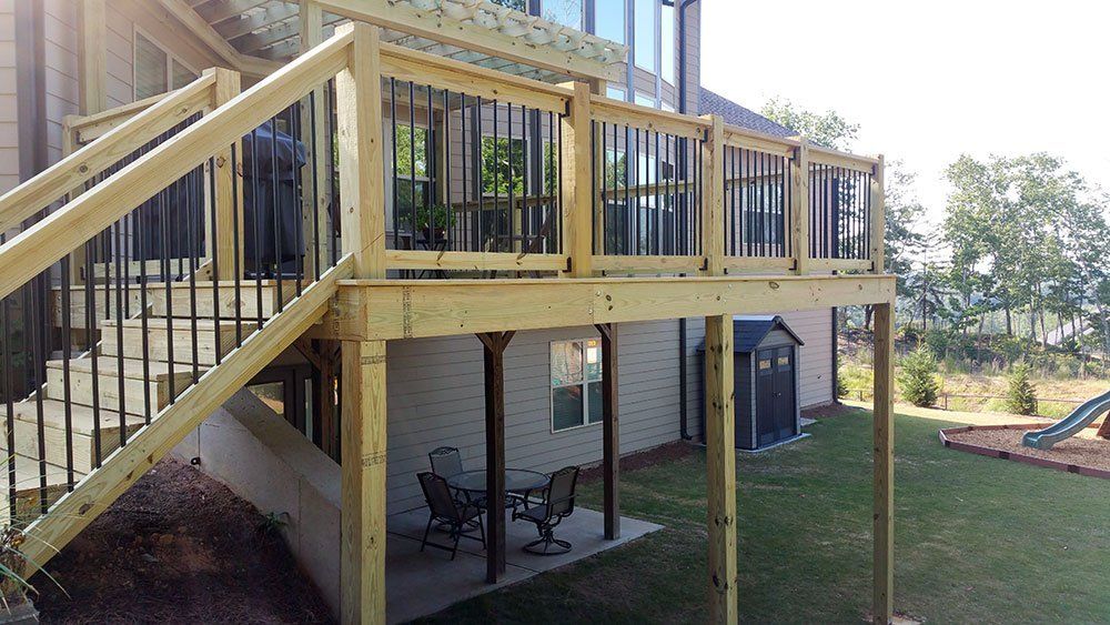 A wooden deck with stairs leading up to it is in the backyard of a house.
