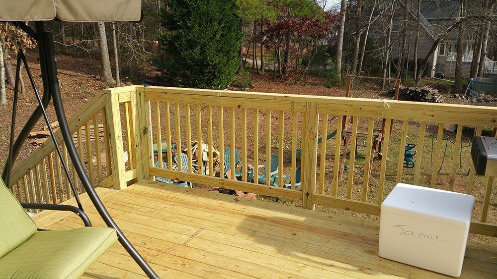 A wooden deck with a swing and a cooler on it.