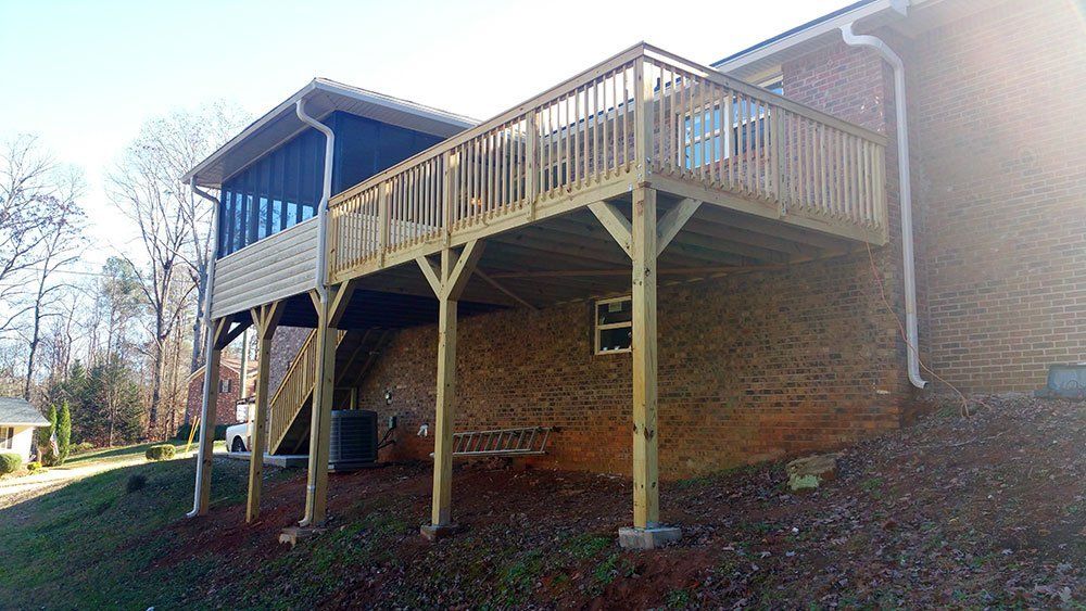 A large wooden deck is attached to the side of a house.