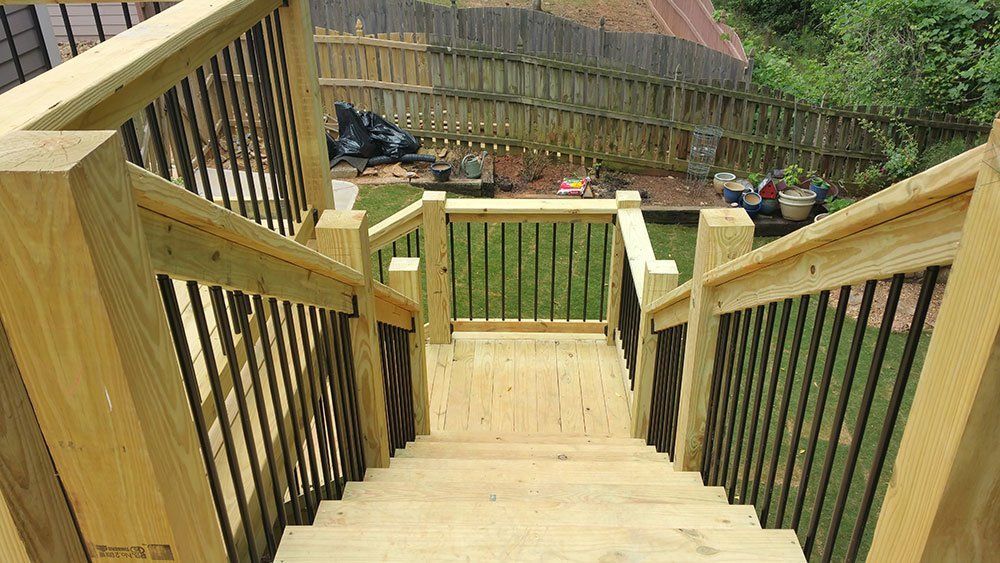 A wooden deck with stairs leading up to it and a fence in the background.