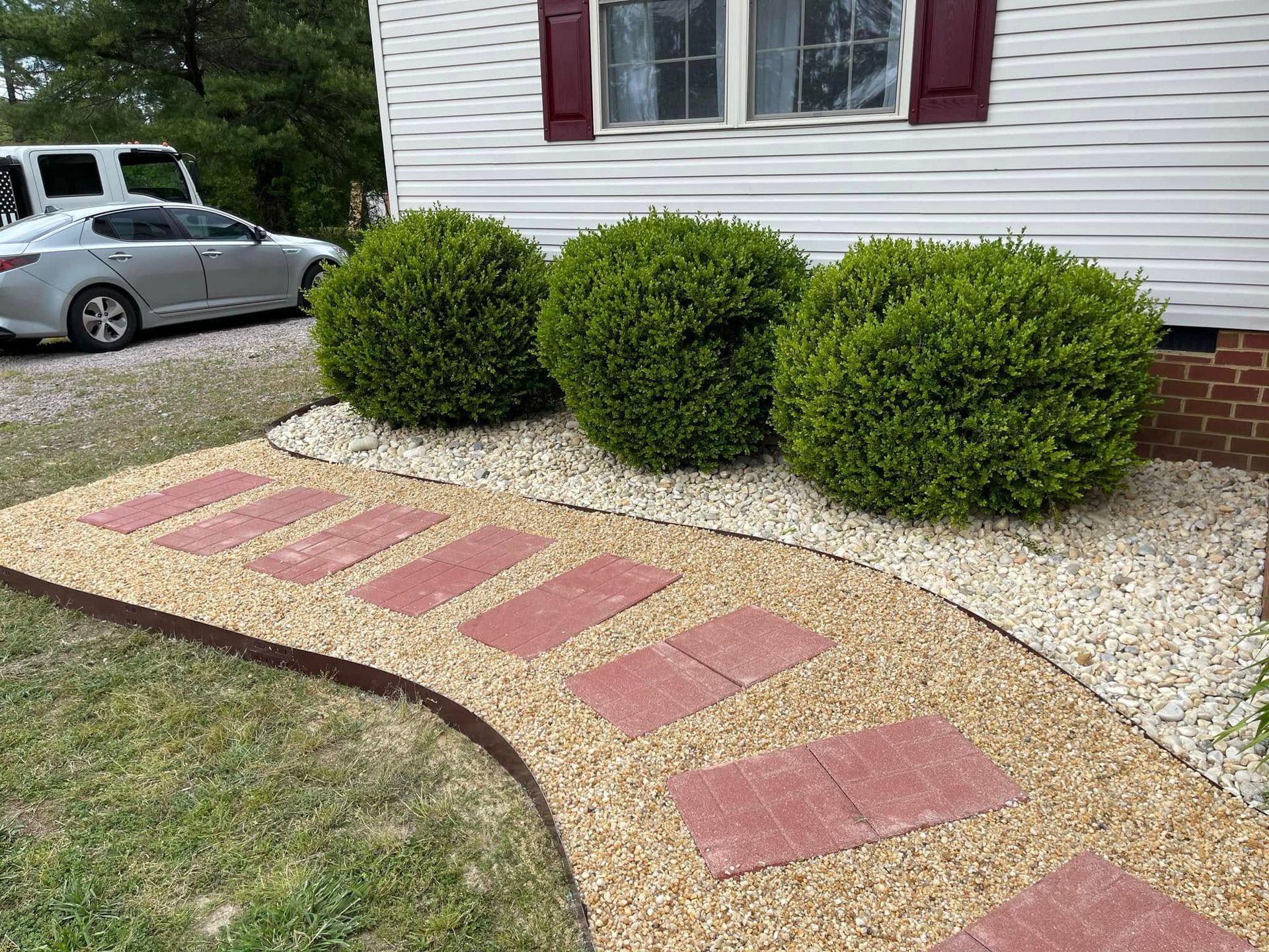 A walkway leading to a house with a car parked in the driveway.