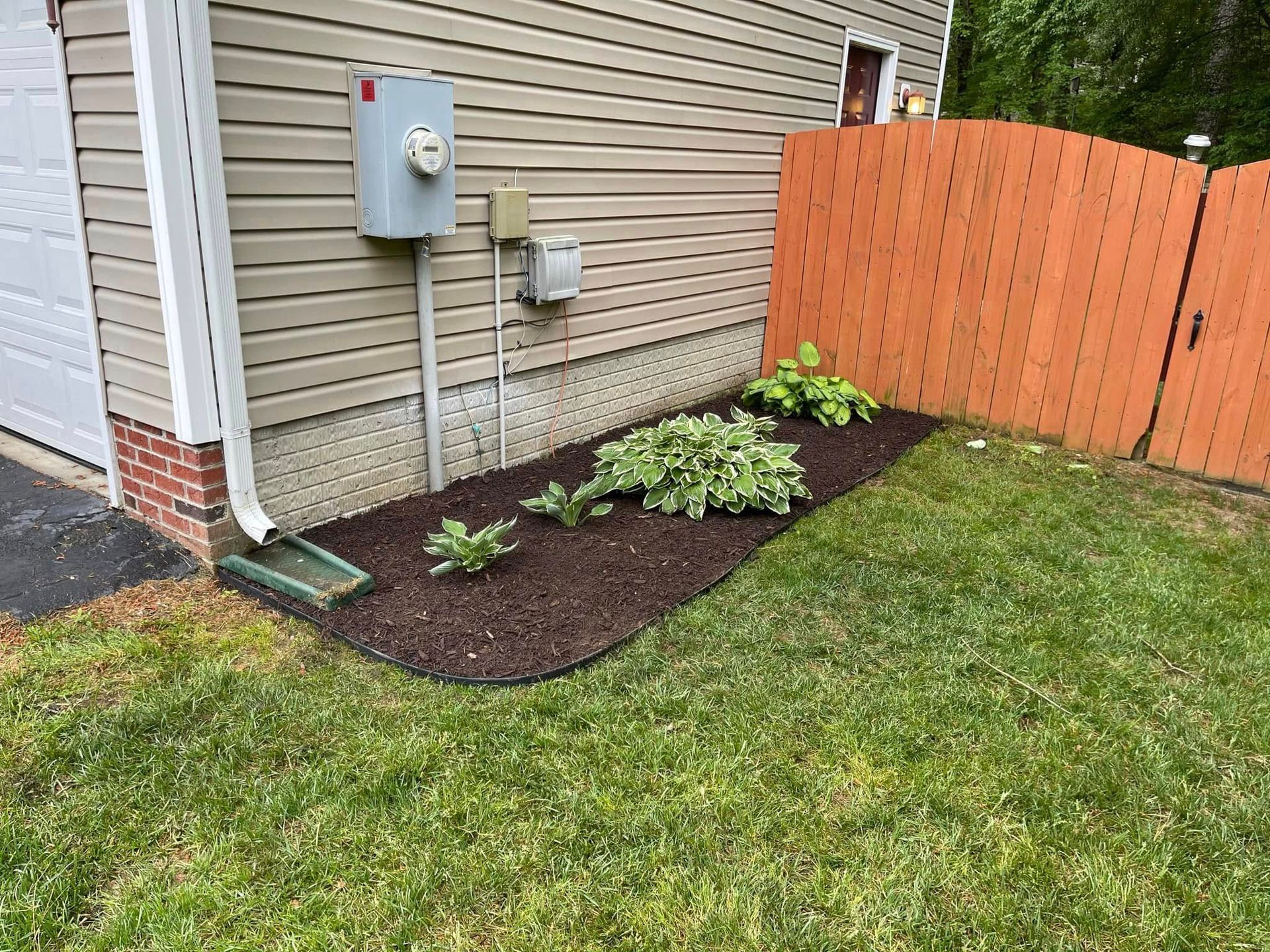 A house with a fence and a garden in front of it.