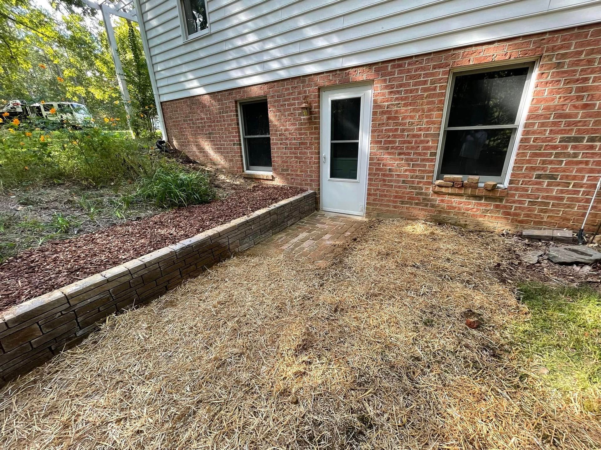 A brick house with a white door and a gravel driveway in front of it.