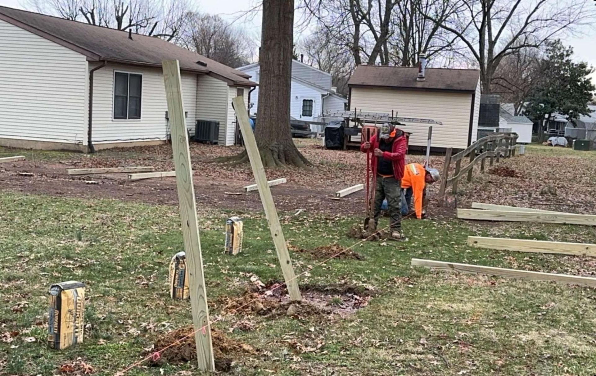 A man is digging a hole in the ground in front of a house.