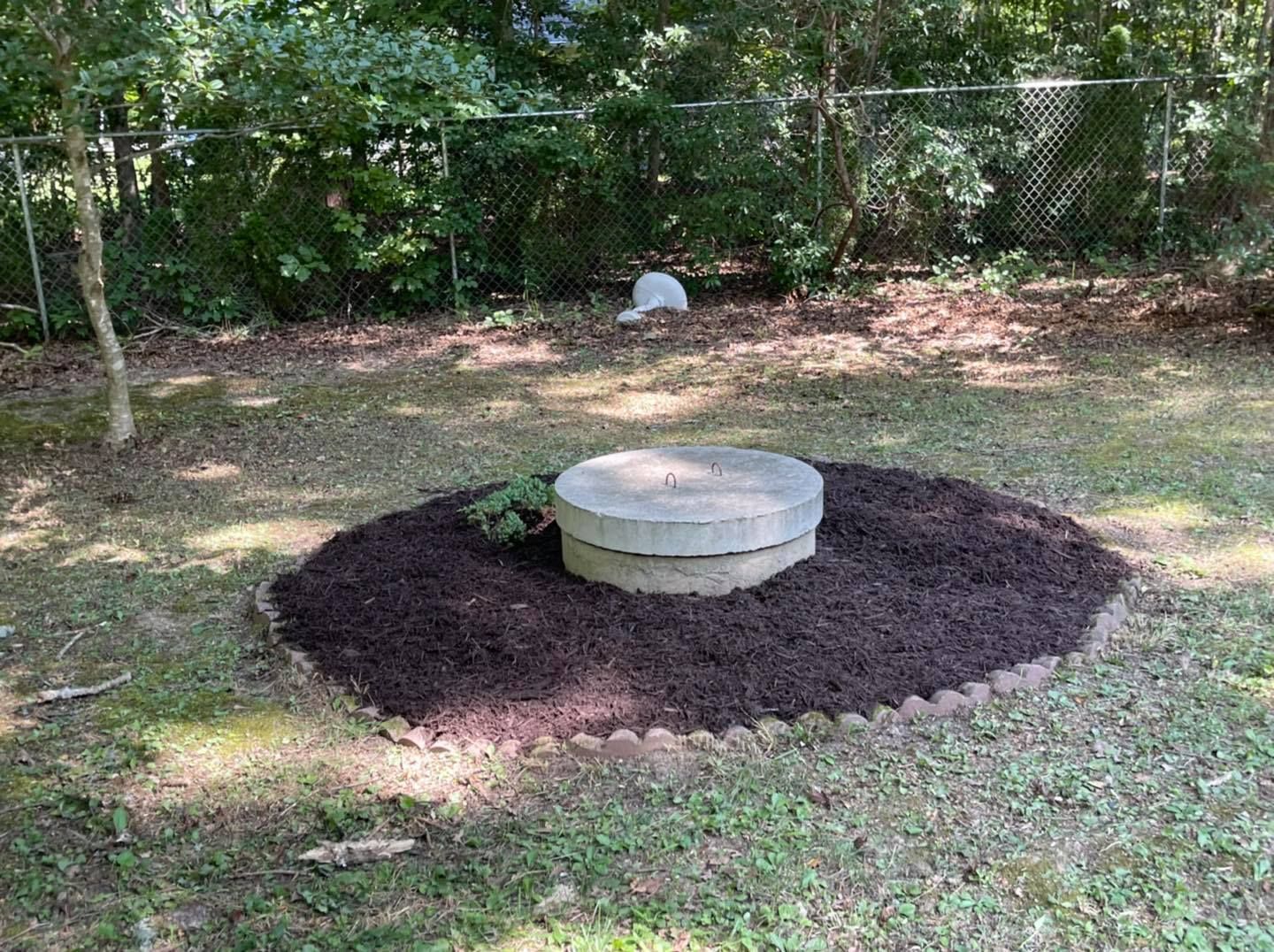 A fire pit is sitting in the middle of a lush green field.