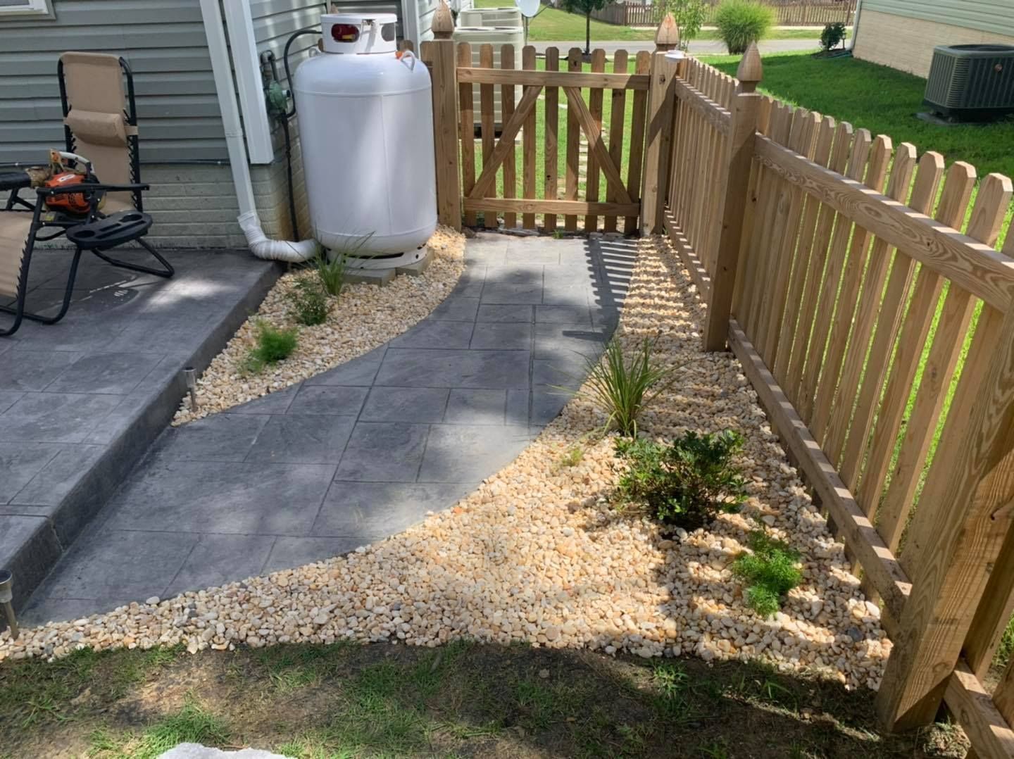 A wooden fence surrounds a patio with a propane tank.