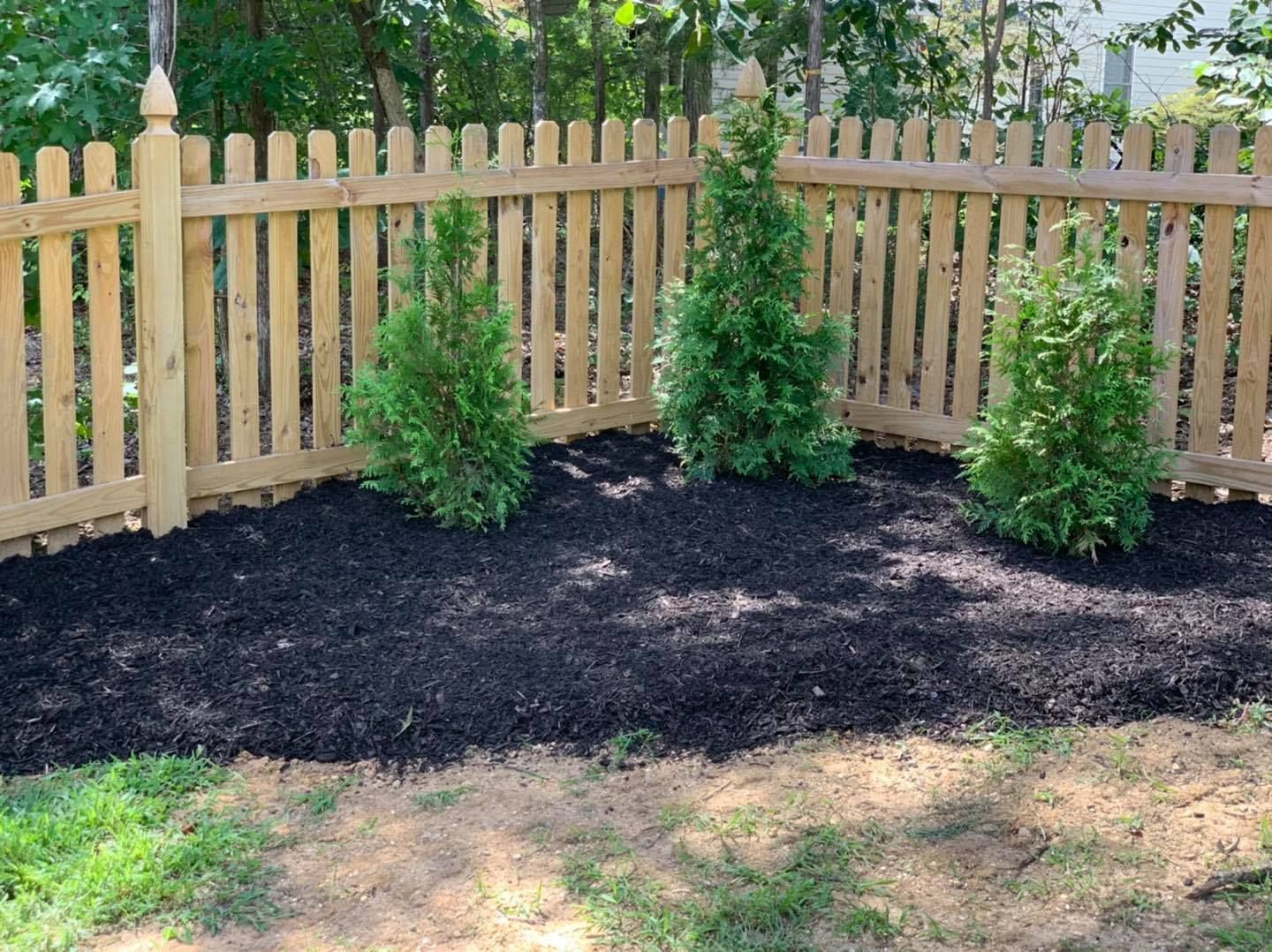 A wooden picket fence surrounds a lush green yard.