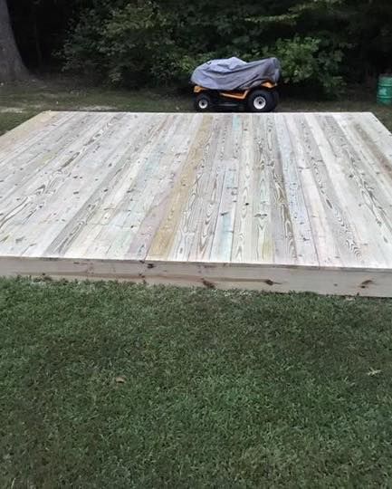 A wooden deck is sitting on top of a lush green lawn.