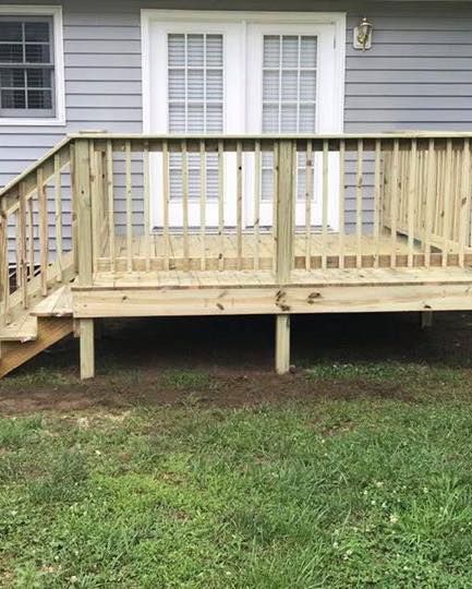 A wooden deck with stairs is in front of a house.
