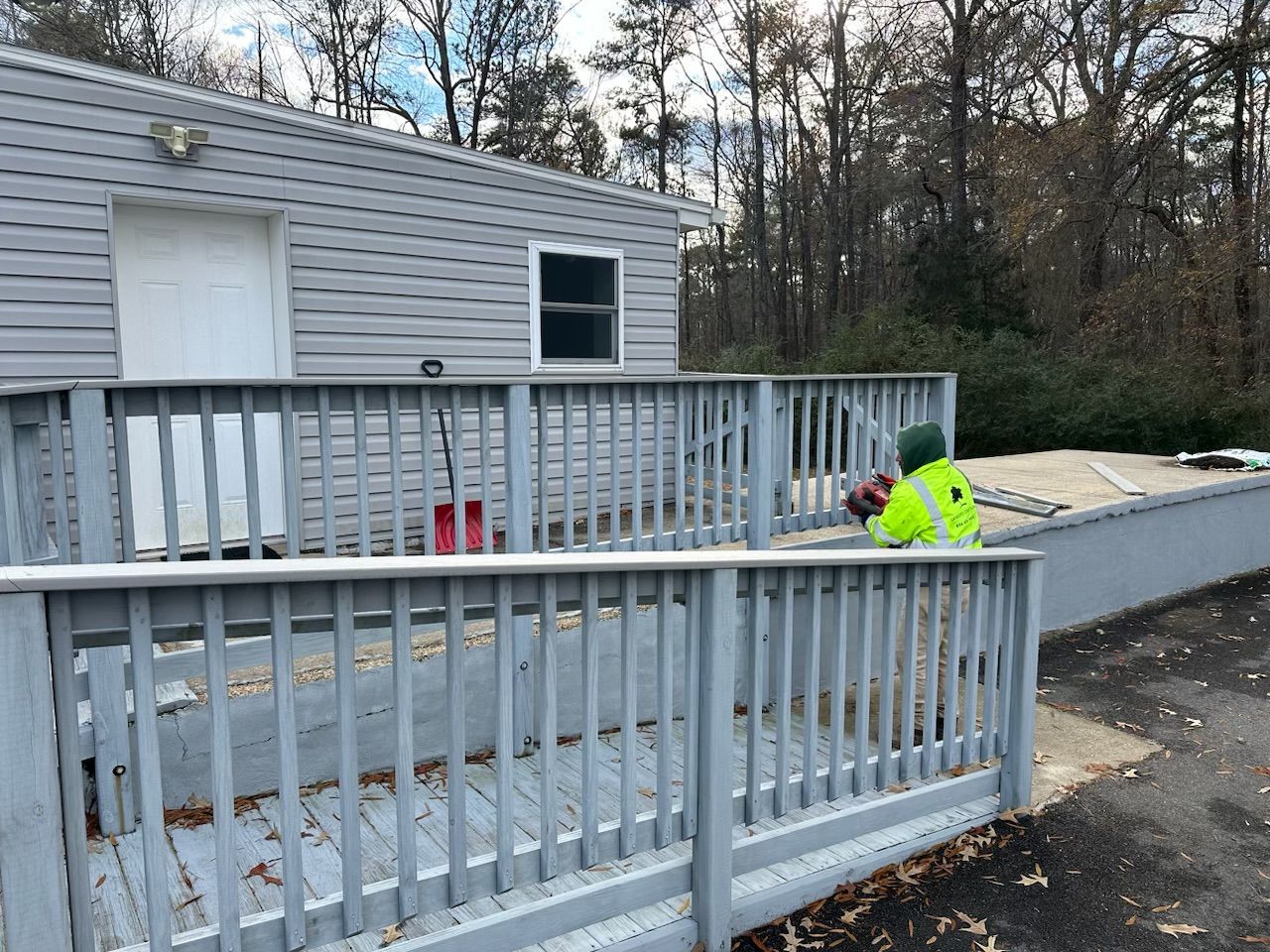 A man in a yellow vest is standing on a deck next to a building.
