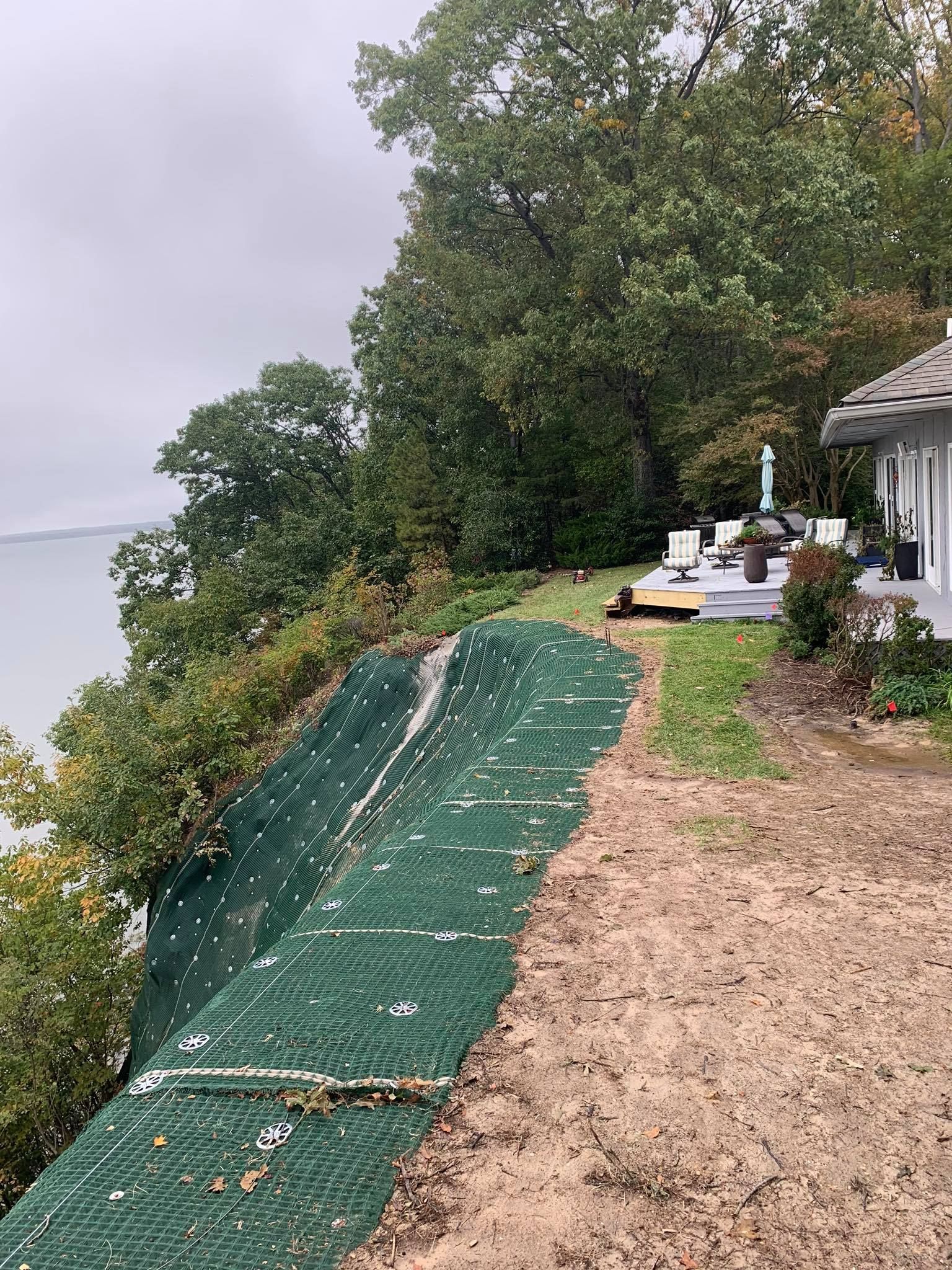 A house is sitting on top of a hill next to a body of water.