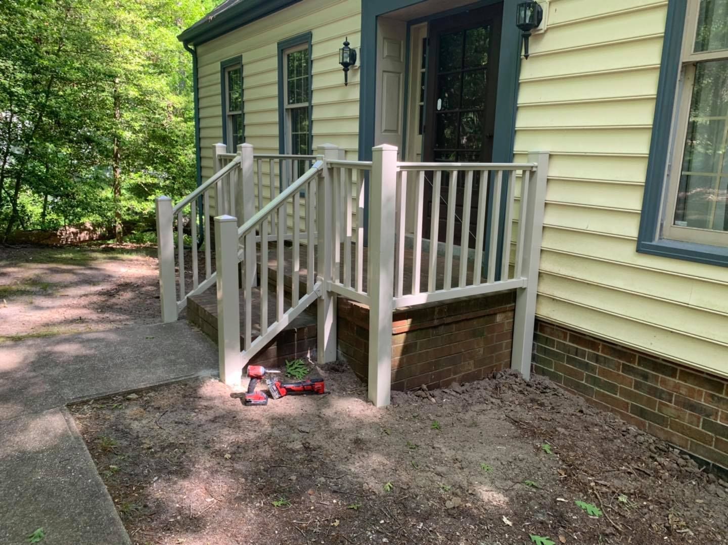 A yellow house with a white porch and stairs.