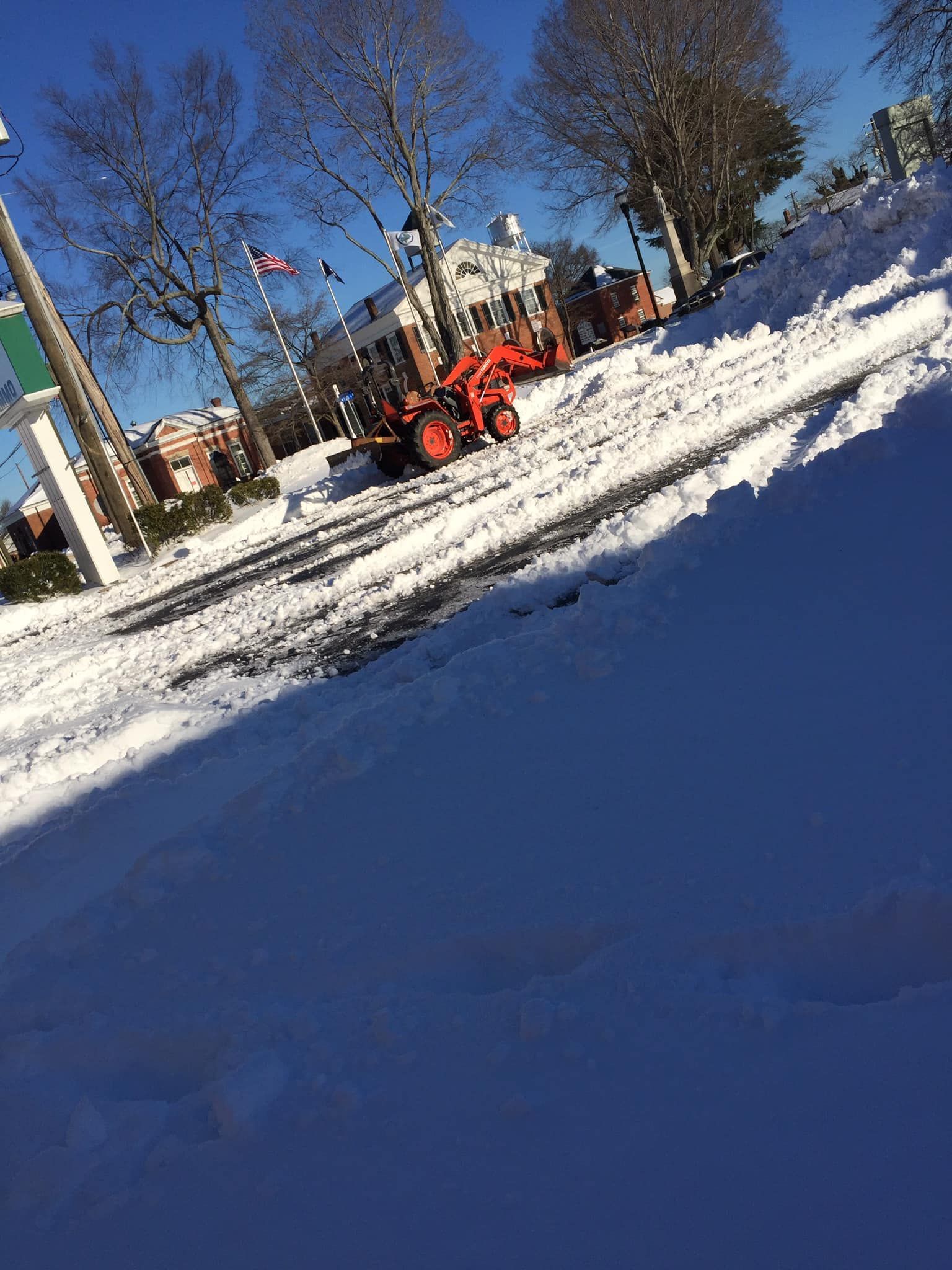 A snow plow is clearing snow from the side of the road.