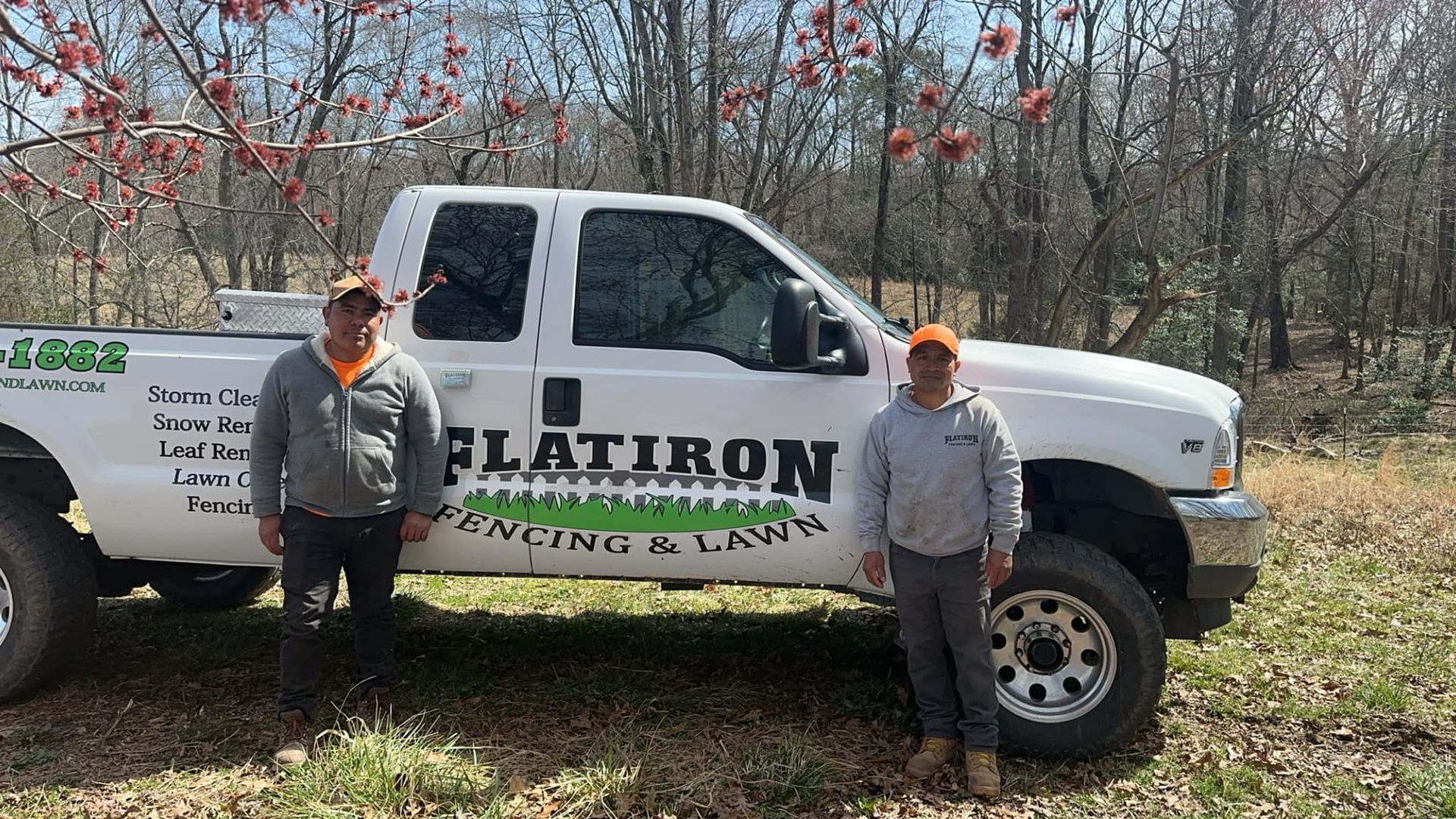 Two men are standing in front of a white truck.