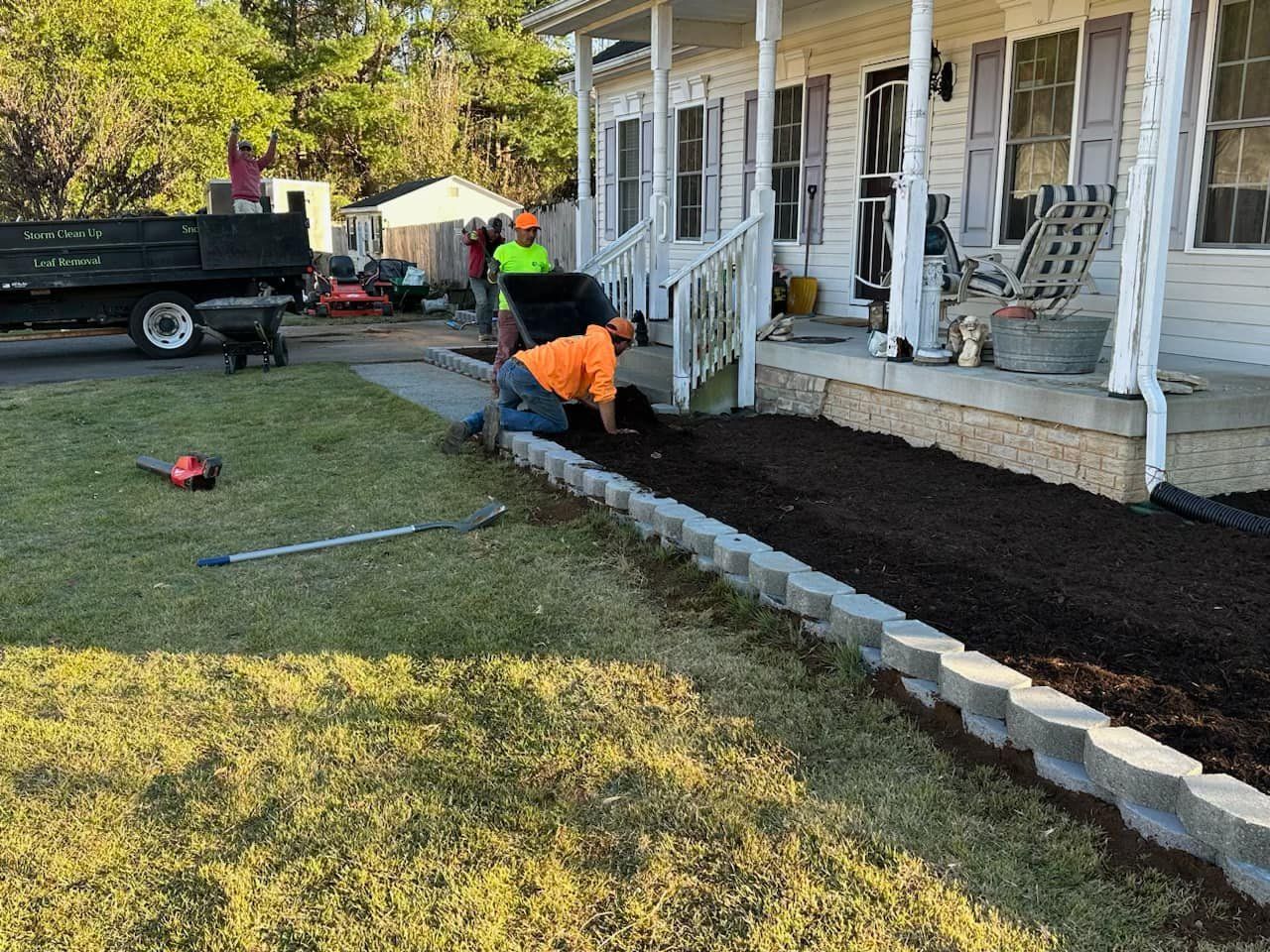 A group of men are working on a lawn in front of a house.