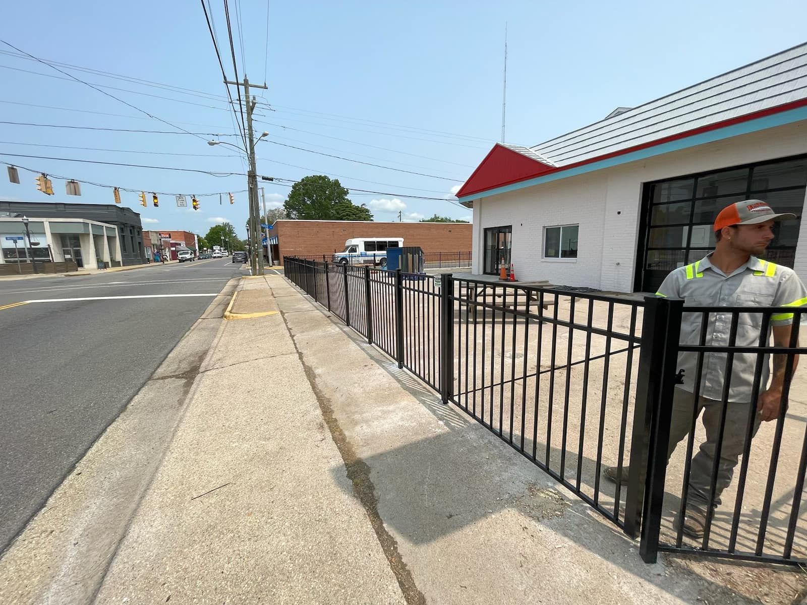 A man is standing behind a metal fence in front of a building.