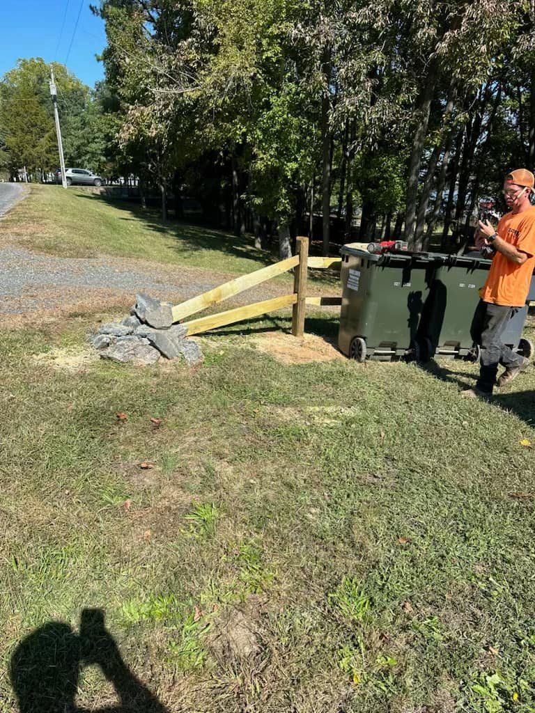 A man is standing in the grass next to a trash can.