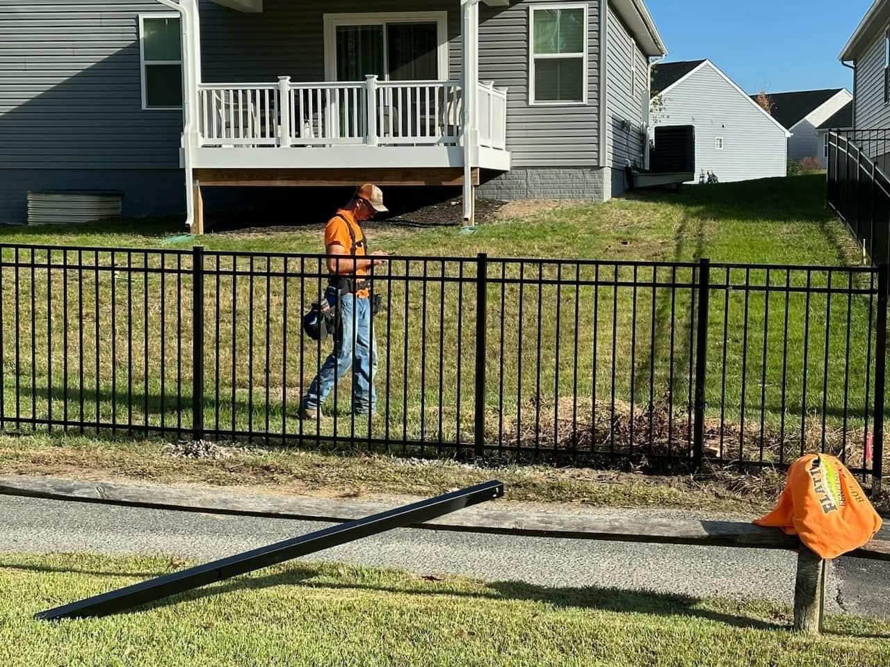 A man is standing next to a fence in front of a house.