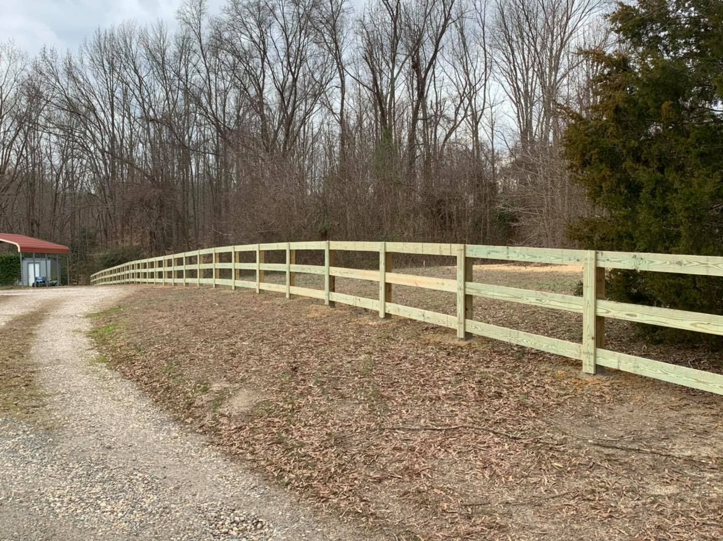 A wooden fence along the side of a dirt road.