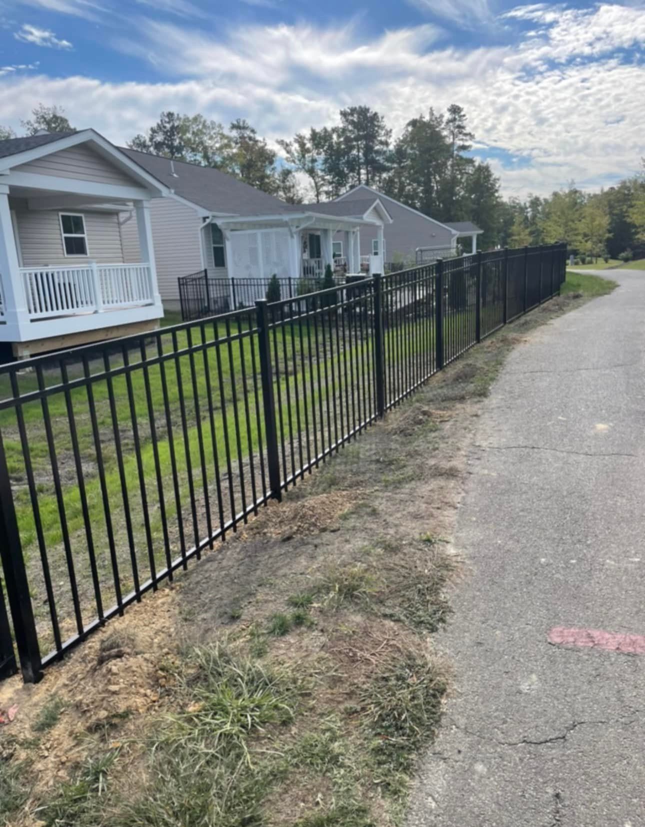 A black fence along a sidewalk next to a house.