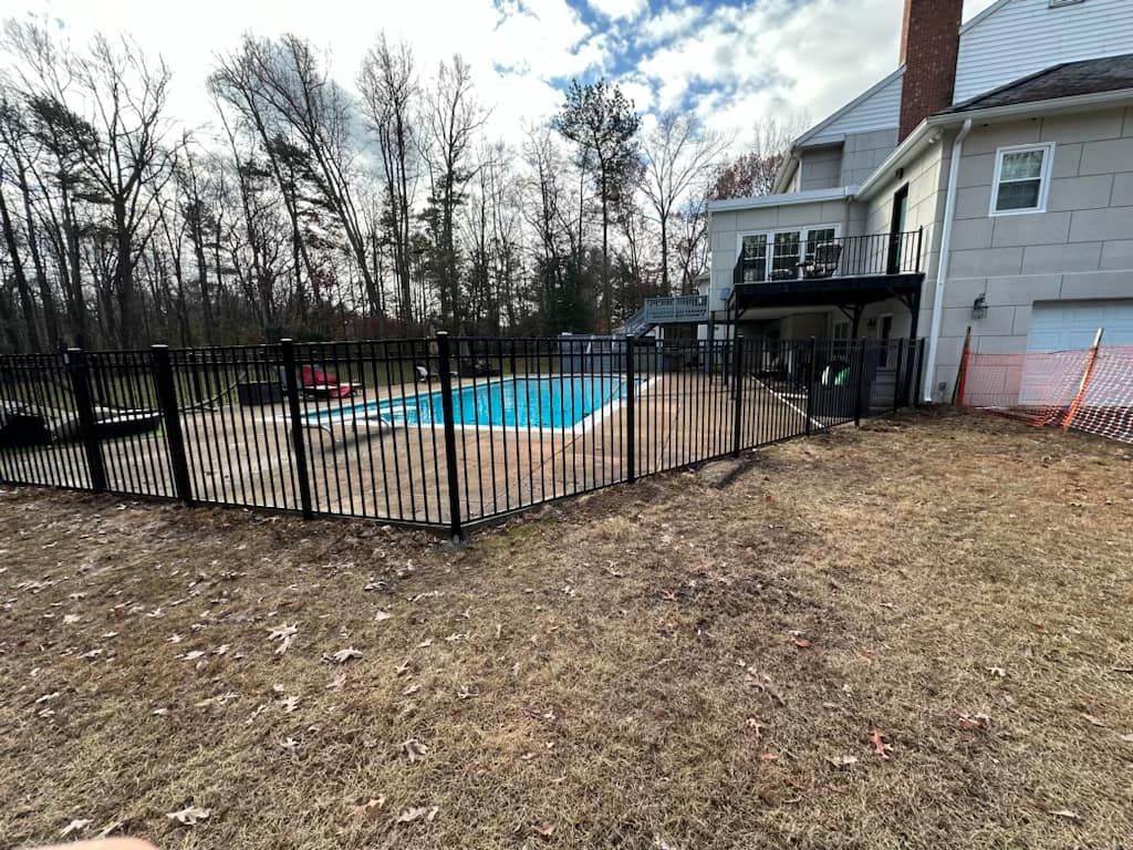 A large house with a swimming pool behind a metal fence.