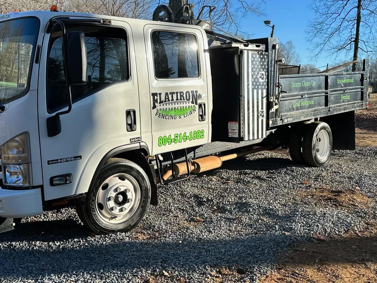 A white flatbed truck is parked in a gravel lot.