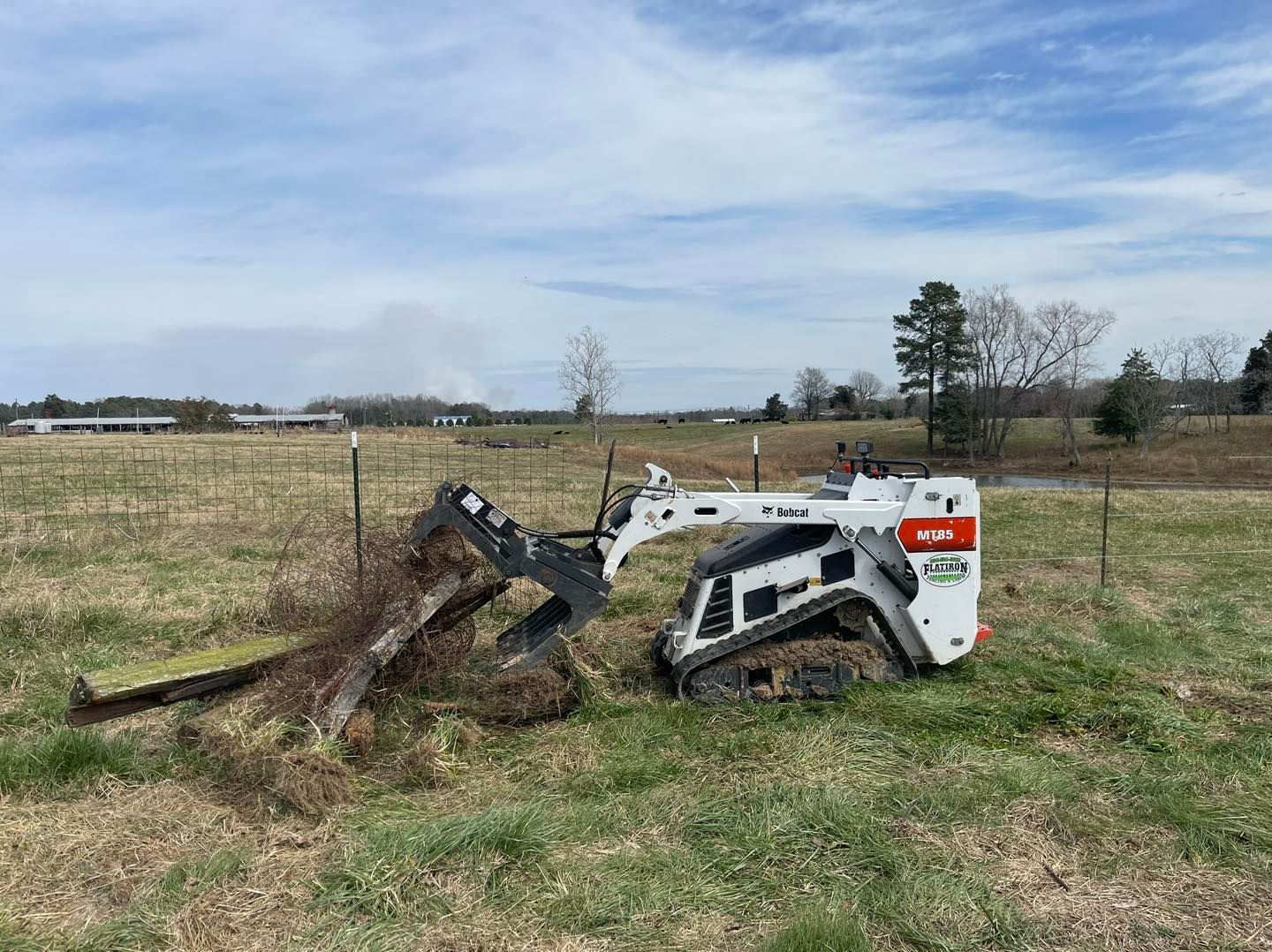 A small bulldozer is sitting in the middle of a grassy field.