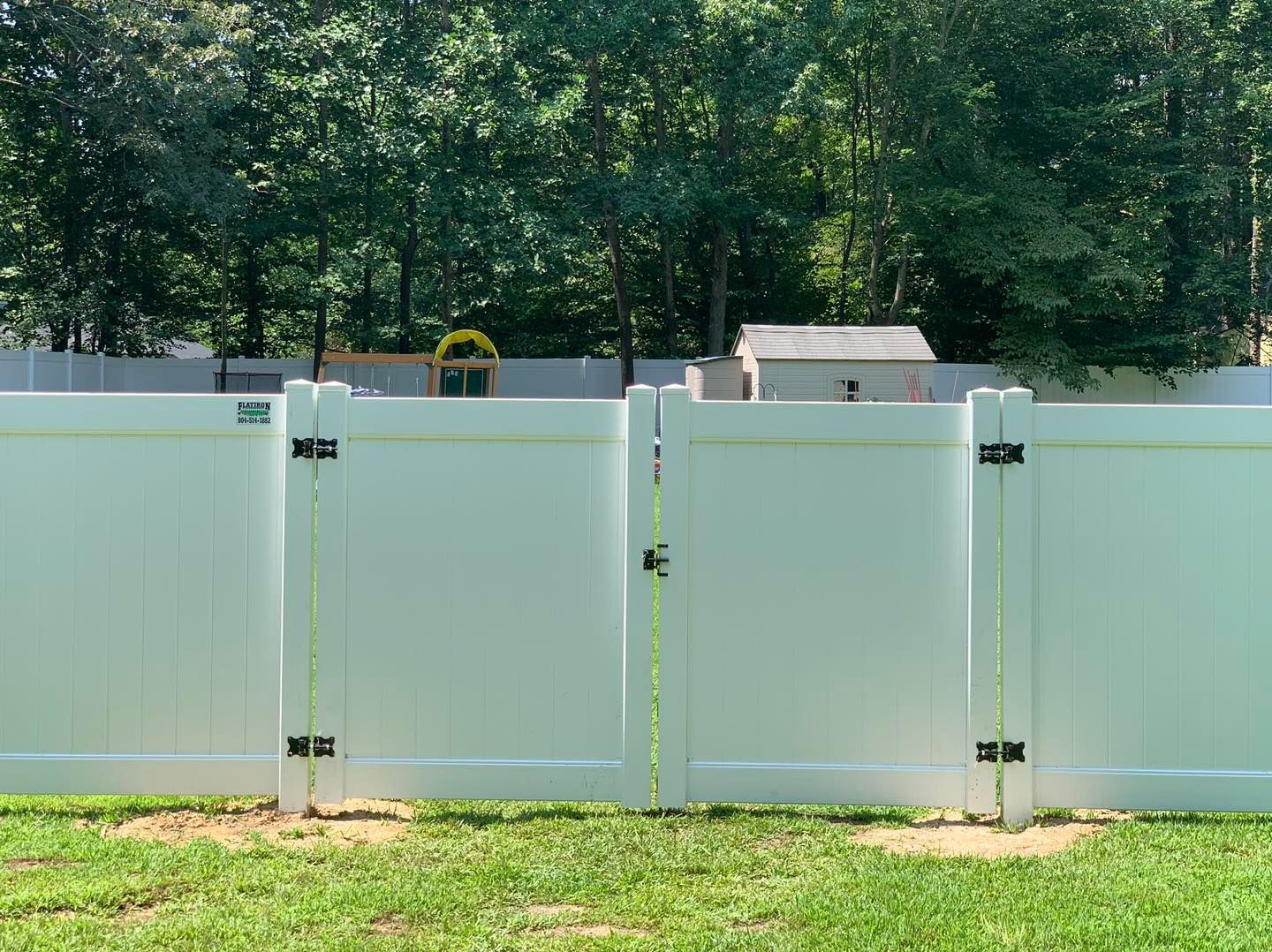 A white fence is sitting in the middle of a lush green field.
