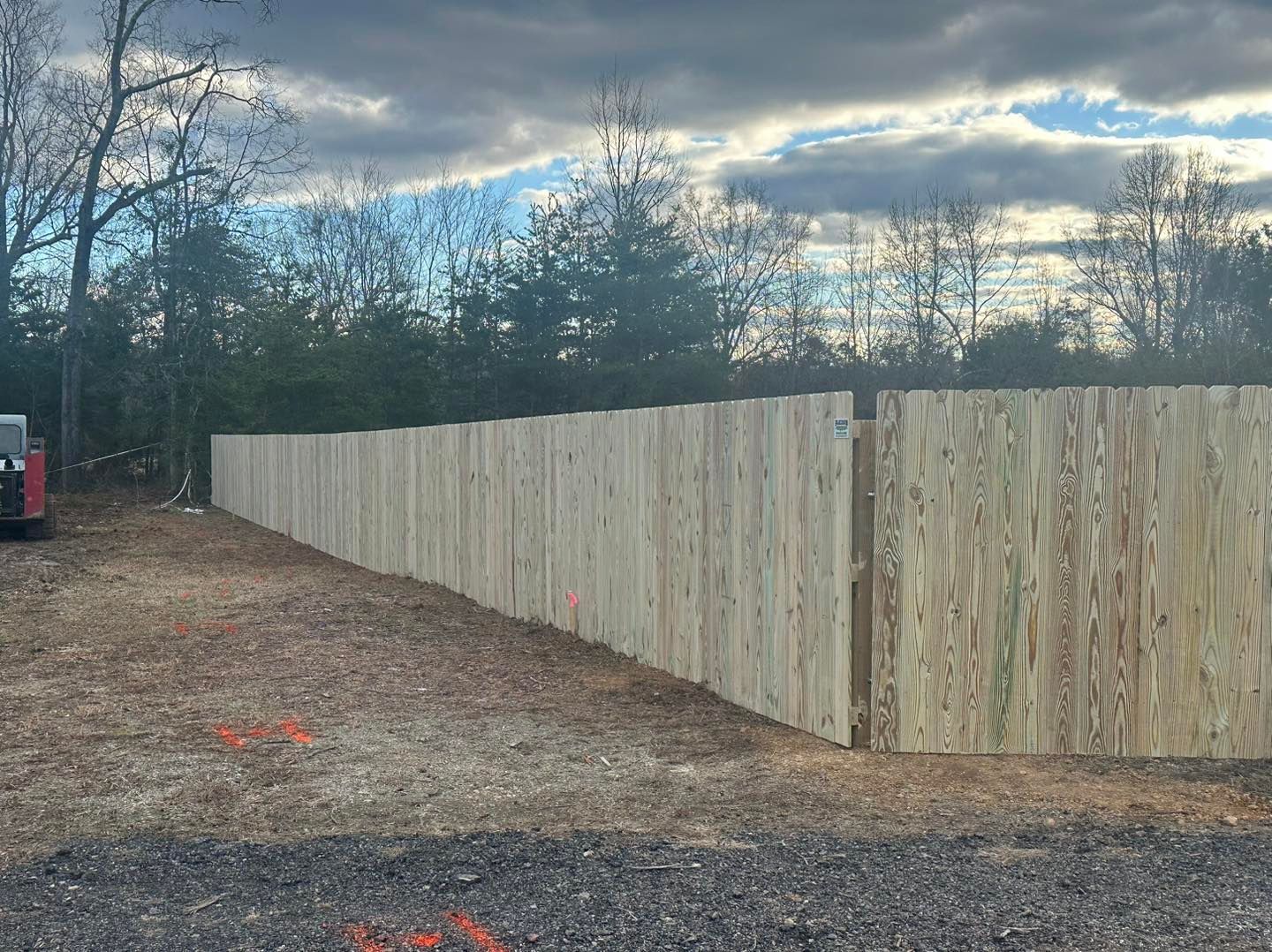 A long wooden fence is sitting in the middle of a dirt field.