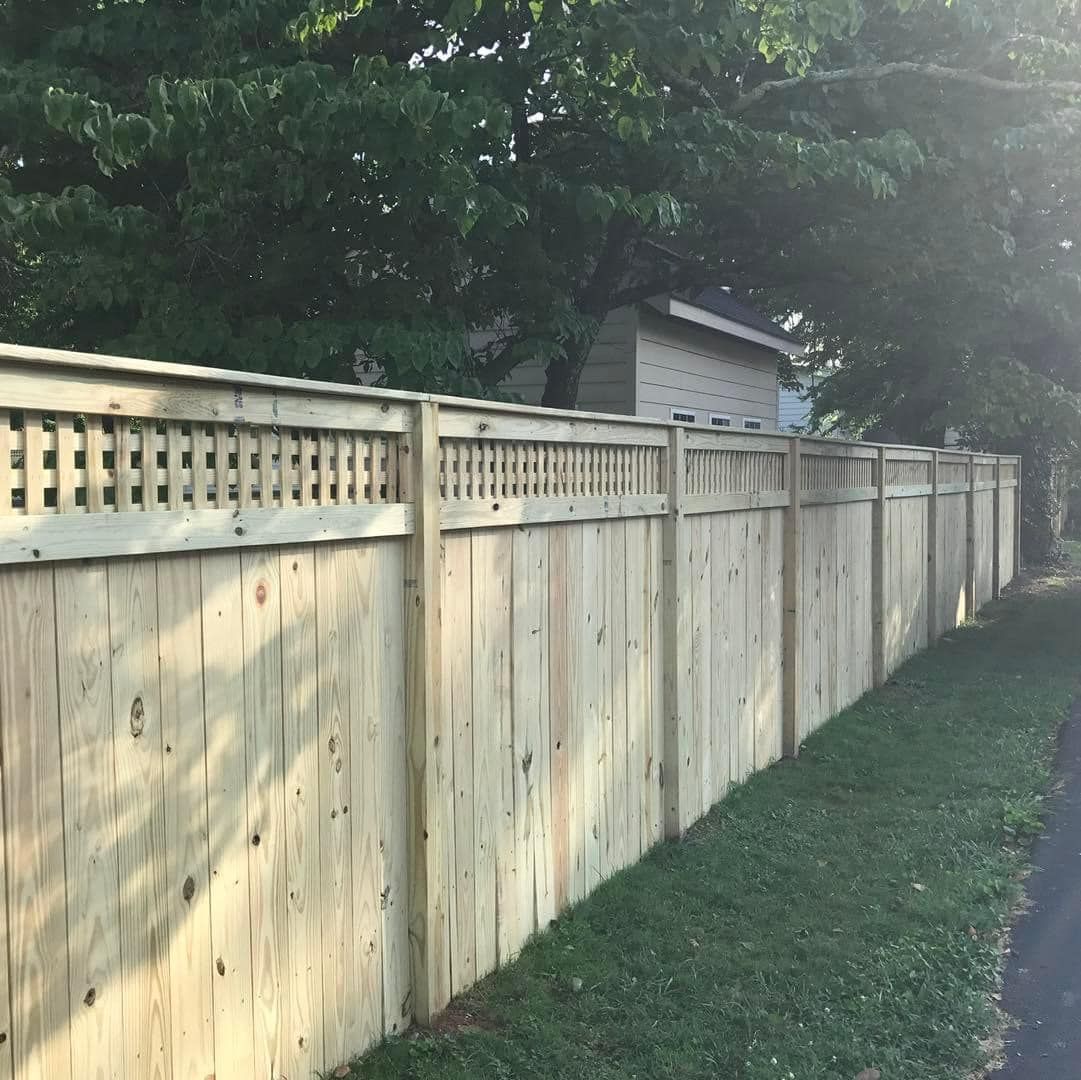 A wooden fence is sitting in the grass next to a house.