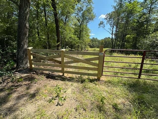 A wooden gate is sitting in the middle of a grassy field.