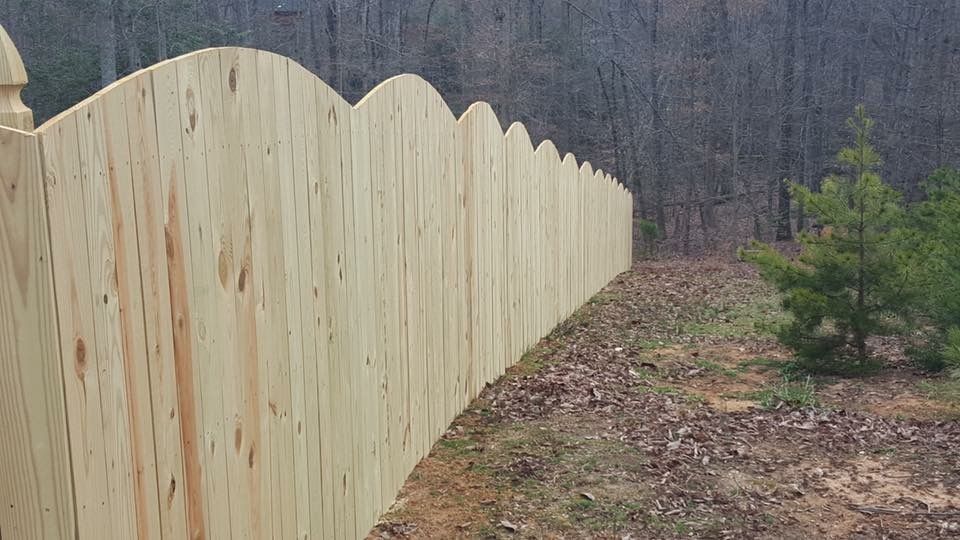 A wooden fence surrounds a dirt path in the woods.