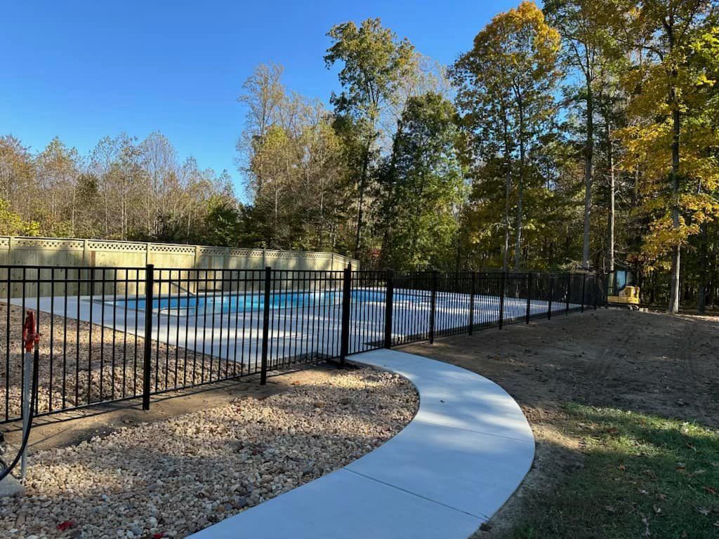 A walkway leading to a swimming pool surrounded by trees.