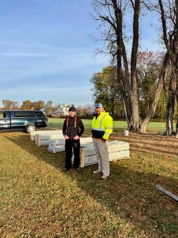 Two men are standing in a field next to a truck.