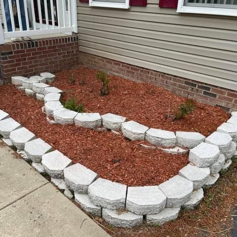 A garden with rocks and mulch in front of a house.