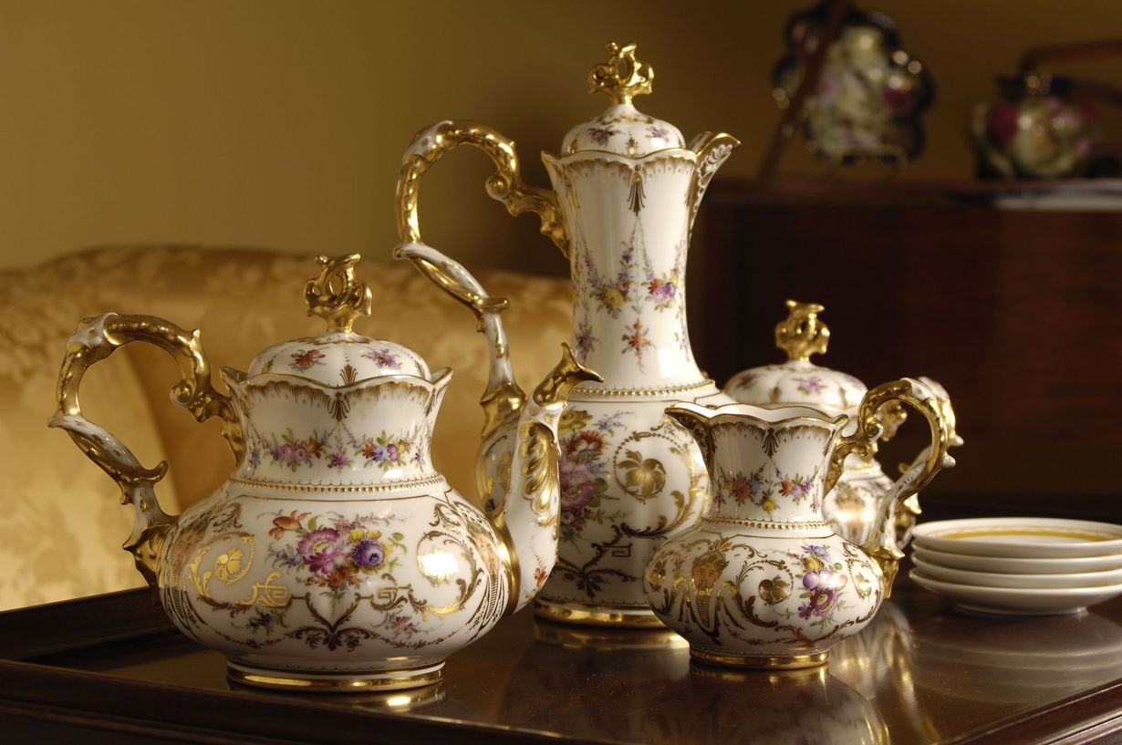 Elegant white-and-gold porcelain tea set with floral accents on a polished table