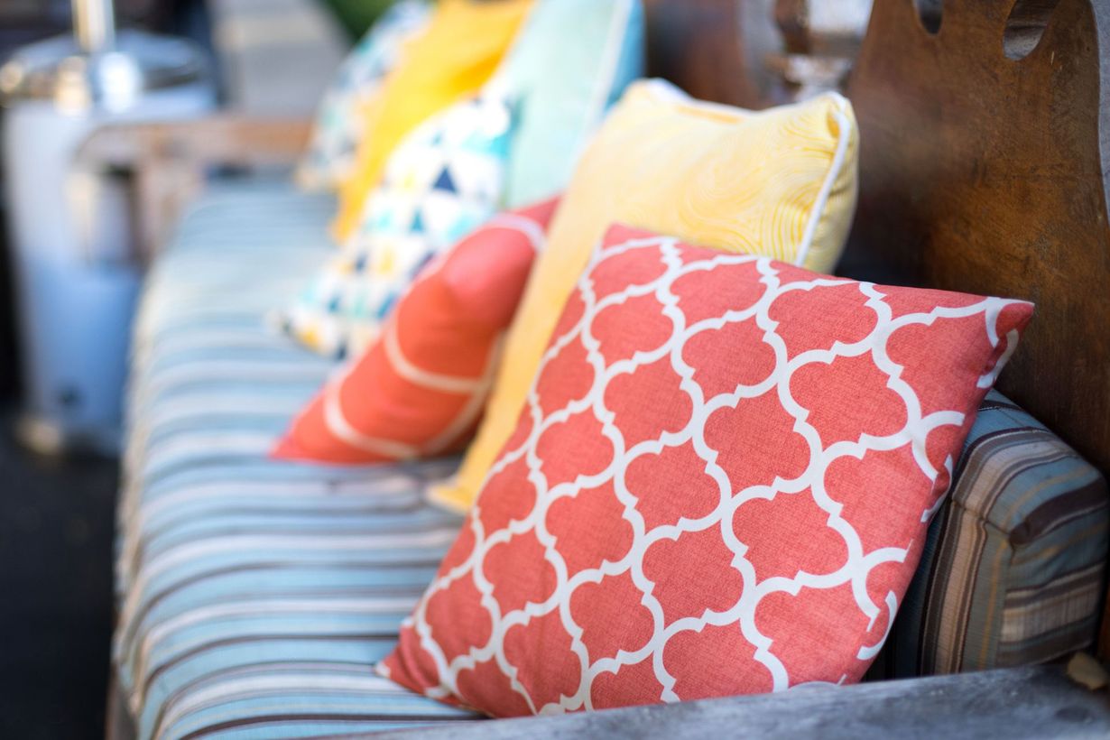 Colorful patterned throw pillows on a striped couch in a cozy living room