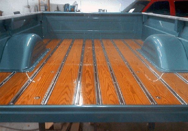 Blue truck bed with glossy, stained wood planks and metal strips.