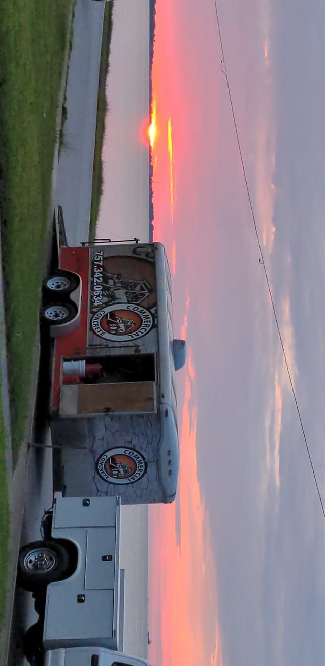 Food truck parked near water at sunset, with birds flying overhead.