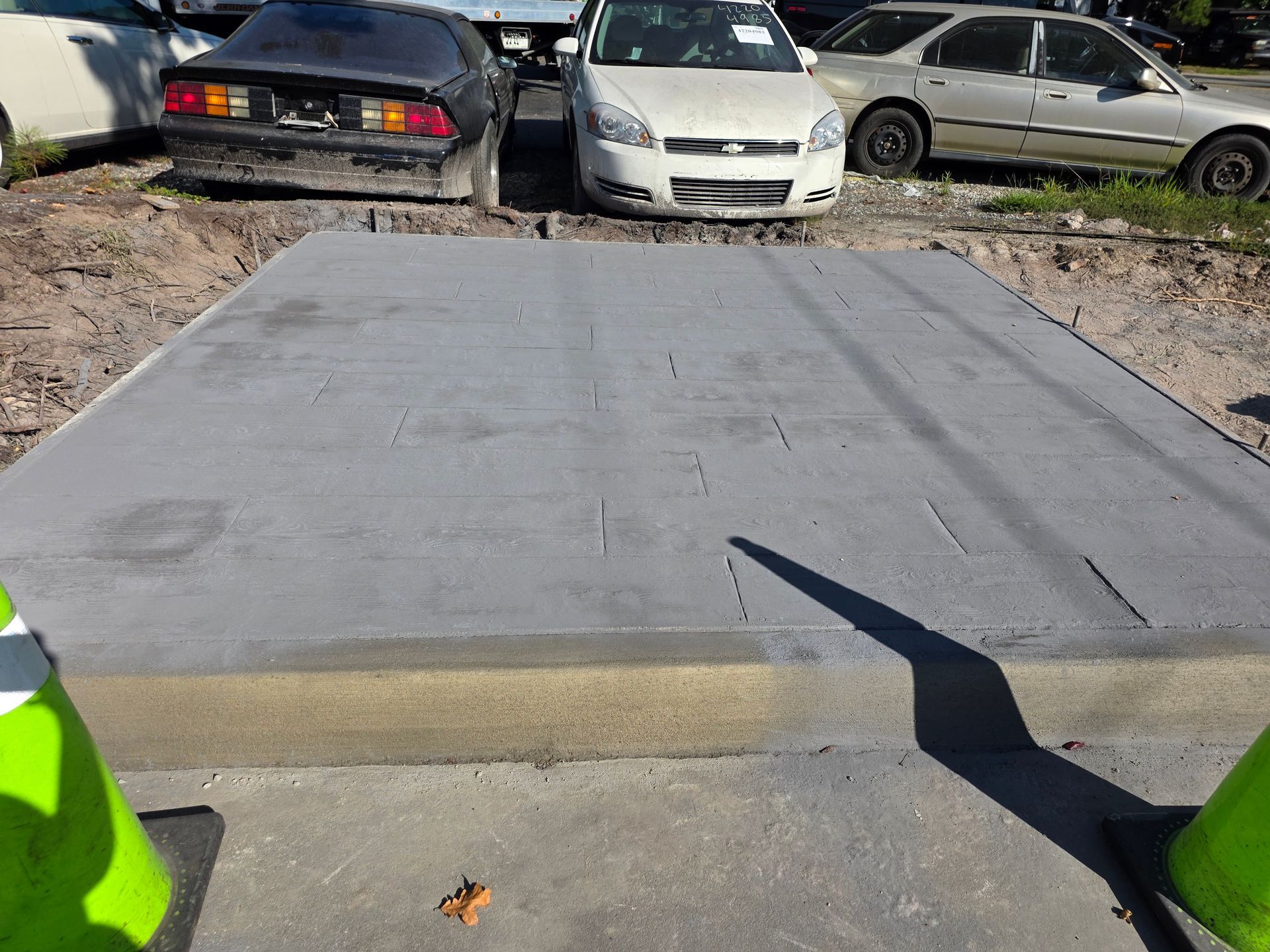 Concrete platform with tire tracks, surrounded by cars and traffic cones.